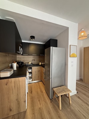 A modern kitchen with a wooden island, stainless steel appliances, and a small wooden stool.