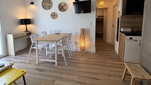 A modern kitchen with a built-in oven, a dining area with a wooden table and chairs, and a TV mounted on the wall. - Apart  with heated pool by Pinarello Villa Services (Lecci)