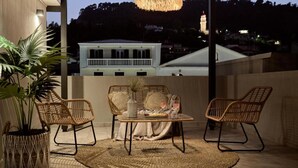 Een terras met rieten meubels, een geweven vloerkleed en een hanglamp.