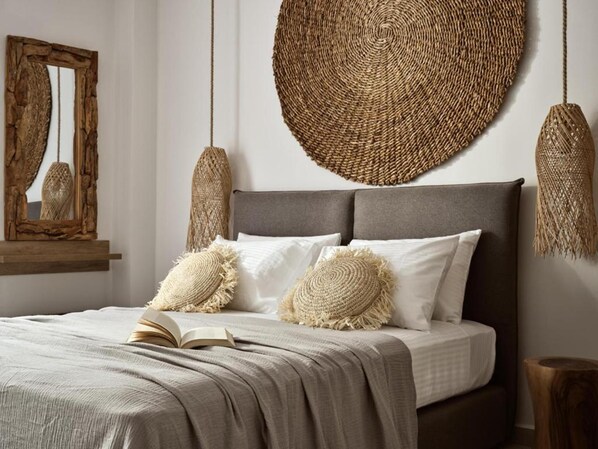 Una cama bien tendida con cabecera gris, dos almohadas blancas y una manta color beige.