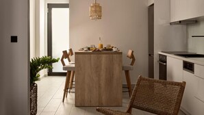 Een moderne keuken met een centraal eiland, houten stoelen en een hangende lamp.