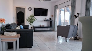 A modern living room with a sofa, a coffee table, and a TV mounted on the wall. - Luxurious Penthouse with Spacious Terrace in Limnaria Gardens, Paphos (Paphos)