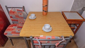 Un pequeño comedor con una mesa de madera, dos tazas blancas y un jarrón decorativo.
