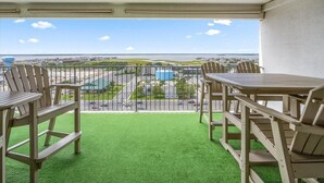 Un balcon donnant sur un parking et des immeubles, aménagé avec des chaises et une table en bois.