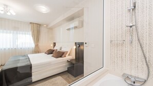 A modern bedroom with a bed, bedside table, and a glass shower enclosure. - Sargas Suite 5 with pool view (Novalja)