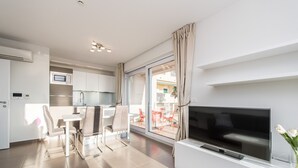 A modern living room with a flat-screen TV, a dining area with a table and chairs, and a kitchen with a microwave and cabinets. - Sargas Suite 6 with city view (Novalja)