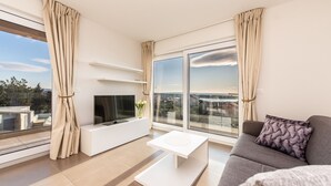 A modern living room with a flat-screen TV, a white coffee table, and a grey sofa with a patterned pillow. - Sargas Suite 6 with city view (Novalja)