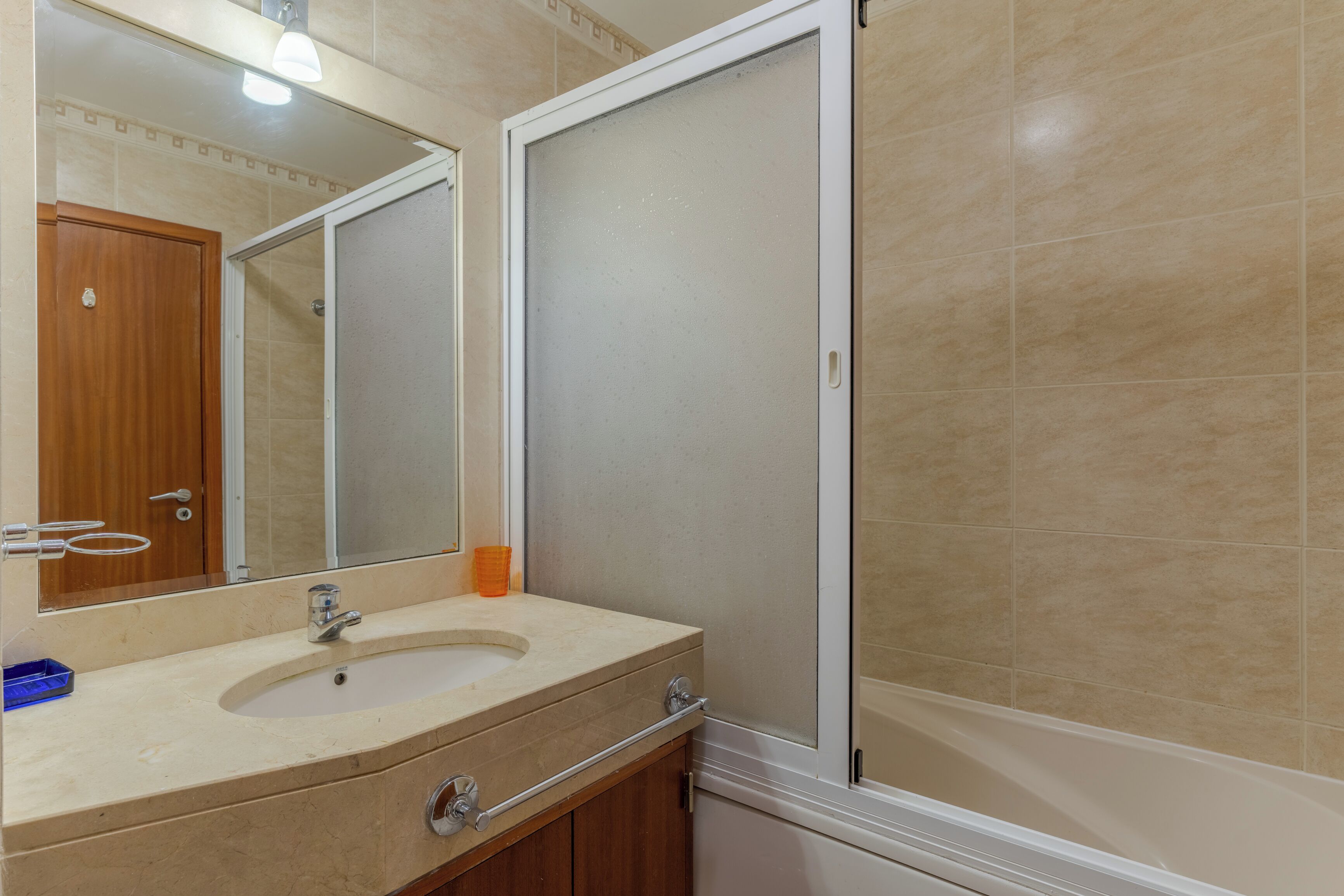 A bathroom with a sink, mirror, and shower enclosure.