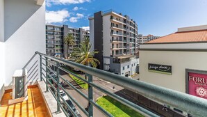A multi-story building with balconies, a palm tree, and a sign for 'pingo doce'. - Ivana Apartment by HR Madeira (Funchal)