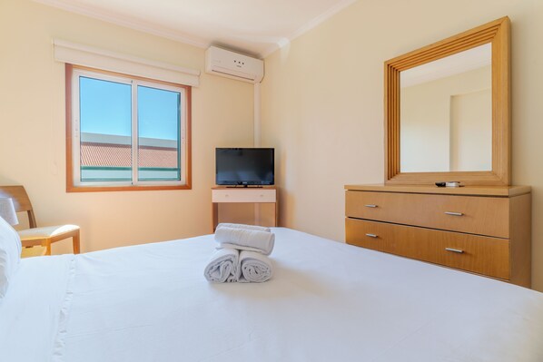 Una habitación de hotel con cama, televisión, cómoda y ventana con vistas.