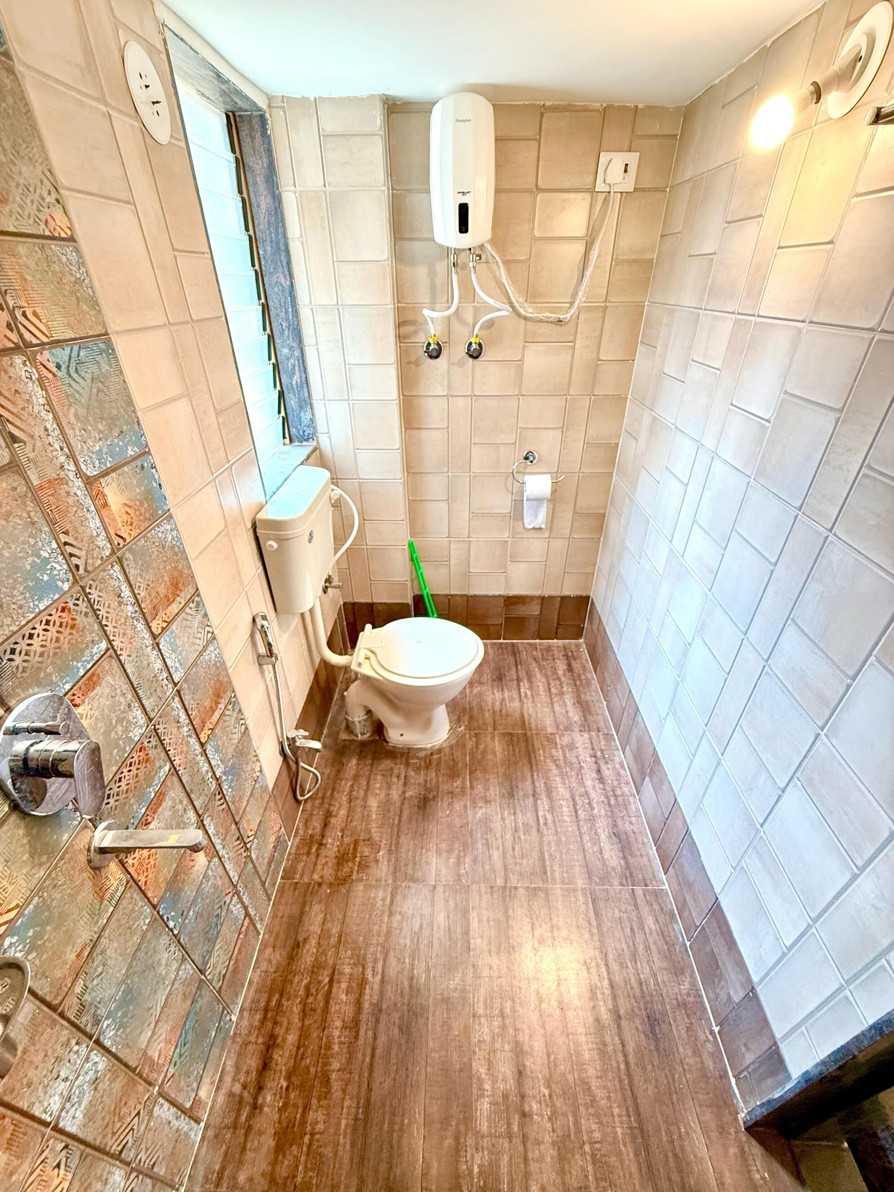 Un baño con inodoro, secamanos y zona de ducha.