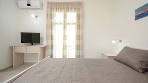 A bedroom with a bed, a desk, a television, and a painting on the wall. - Villa Sand Lily with private pool (Naxos)