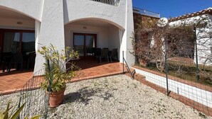 Un edificio de dos pisos con un balcón, un patio cubierto y un camino de entrada de grava.