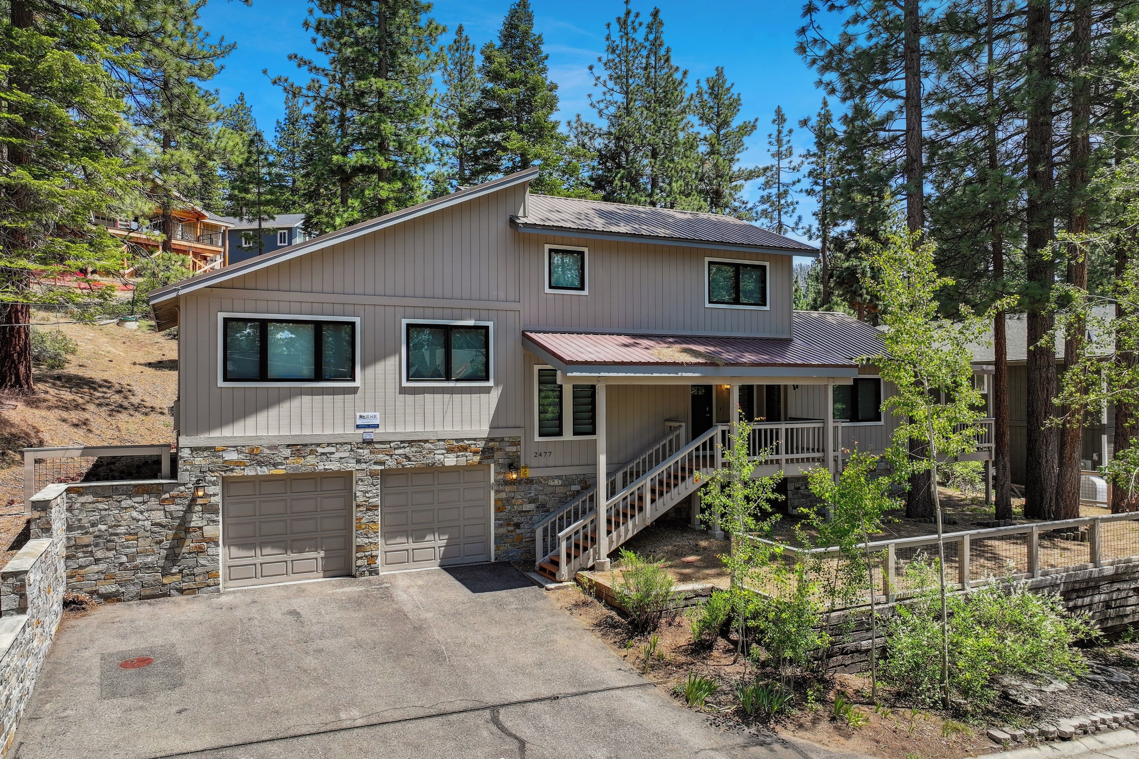 A two-story house with a stone foundation, a garage, and a covered porch.