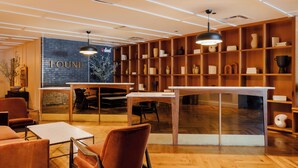 A modern interior with wooden shelves, tables, and chairs, and a large window with the word "FOUND" on the wall. - FOUND Hotels, Chicago, Series by Marriott (Chicago)