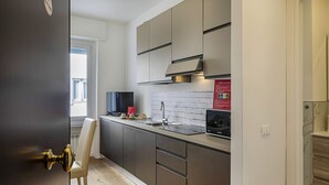 A modern kitchen with grey cabinets, a stainless steel sink, and a black microwave. - Zena Tower by Wonderful Italy (Genoa)