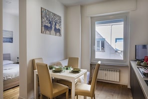 Ett kompakt hotellrum med en matplats, en säng, ett element och ett fönster med persienner.