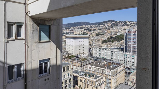 A high-rise building with multiple windows and balconies, overlooking a densely packed urban area with various architectural styles. - Zena Tower by Wonderful Italy (Genoa)