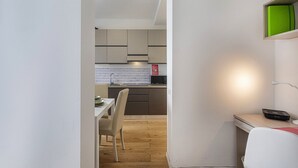 A modern kitchen with a white countertop, a microwave, and a sink. There is a dining area with a table and chairs. - Zena Tower by Wonderful Italy (Genoa)