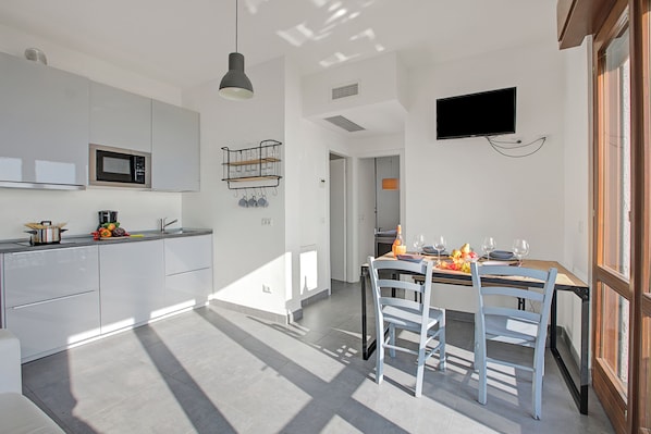 A modern kitchen with white cabinets, a microwave, and a hanging light fixture. - Casa Dei Nonni Tremosine Apartments (Tremosine)