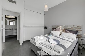 Un dormitorio moderno con una cama bien hecha, una mesita de noche y una lámpara colgante.