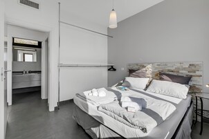 Una camera da letto moderna con un letto rifatto, un comodino e una lampada a sospensione.