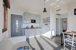 A modern kitchen with white cabinets, a microwave, and a hanging pot rack.