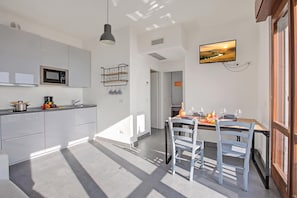 A modern kitchen with white cabinetry, a microwave, and a hanging wine rack. - Casa Dei Nonni Tremosine Apartments (Tremosine)