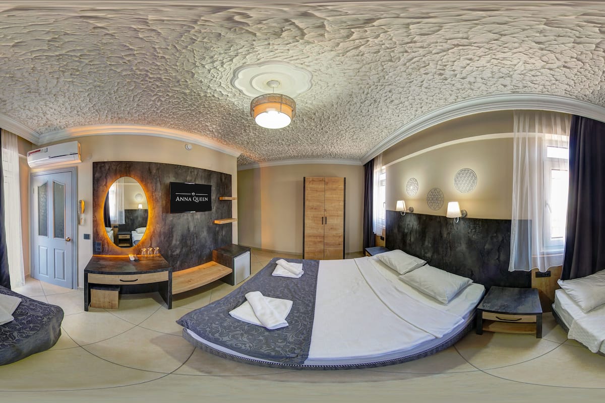 Una habitación con una cama curvada, un tocador con espejo y un techo con diseño texturizado.