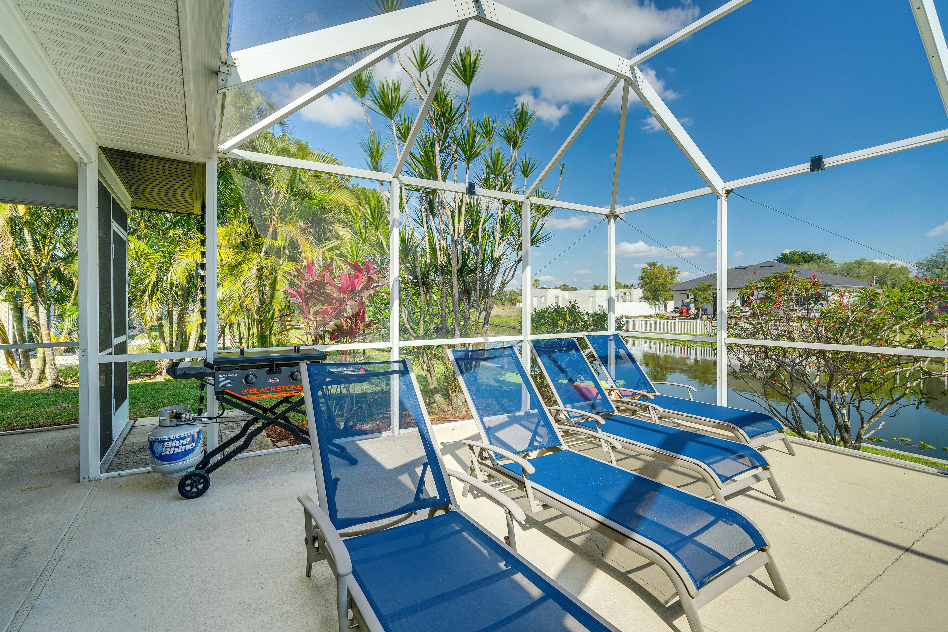 Un espacio al aire libre cubierto con sillones azules, una parrilla y una fuente de agua.
