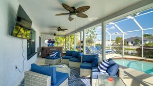 A covered outdoor area with wicker furniture, a pool, and a ceiling fan. - Canal-front Gem w/ Hot Tub, Foosball in Cape Coral (Cape Coral)