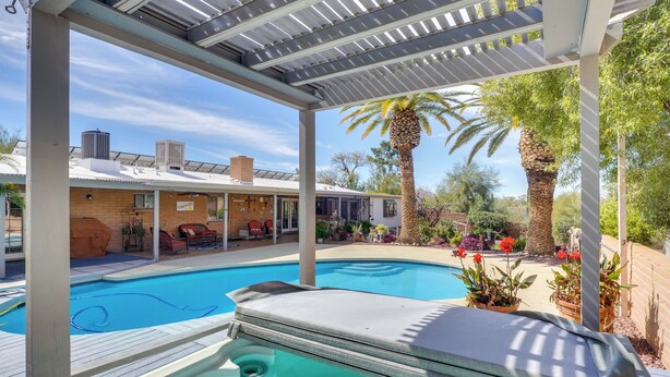 Ein Poolbereich mit Whirlpool, überdachter Terrasse und Sitzgelegenheiten im Freien.