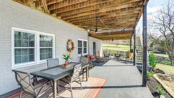 A covered patio area with a table and chairs, a wooden ceiling, and a view of the backyard.