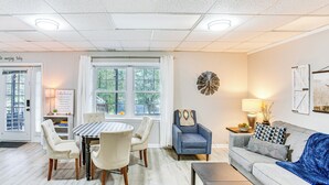 Una sala de estar bien iluminada con una mesa de comedor, sillas, un sofá y una mesa de centro.