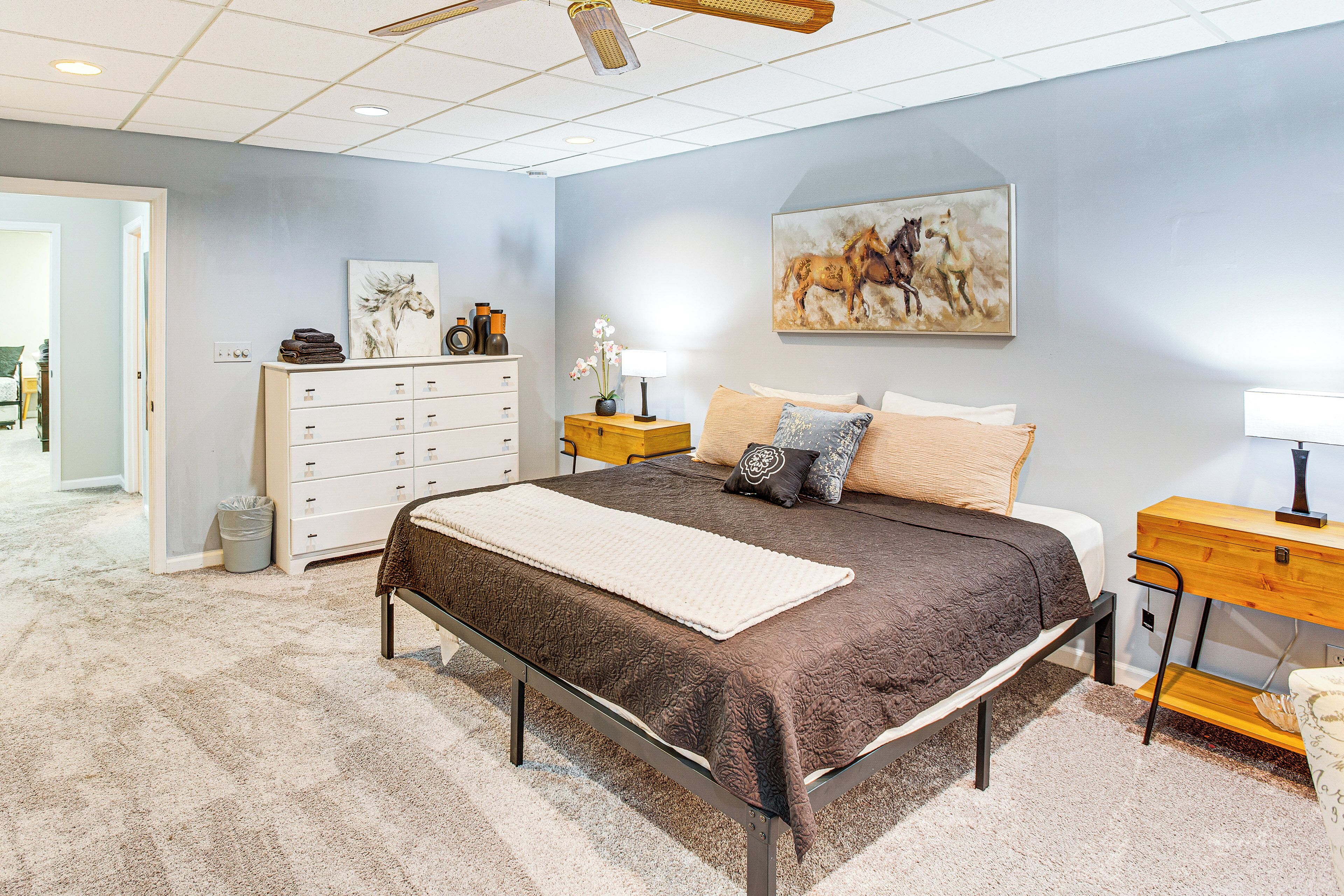 A bedroom with a large bed, a dresser, a nightstand, and a painting on the wall.