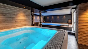A modern bathroom with a large bathtub, wooden walls, and a black ceiling. - Le Baillage (Salers)