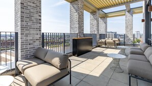 A rooftop terrace with outdoor seating, a bar, and a view of the cityscape. - Student Only Winfield Court (Nottingham)