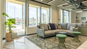 A modern living room with a sectional sofa, a coffee table, and a green chair. - Student Only Winfield Court (Nottingham)