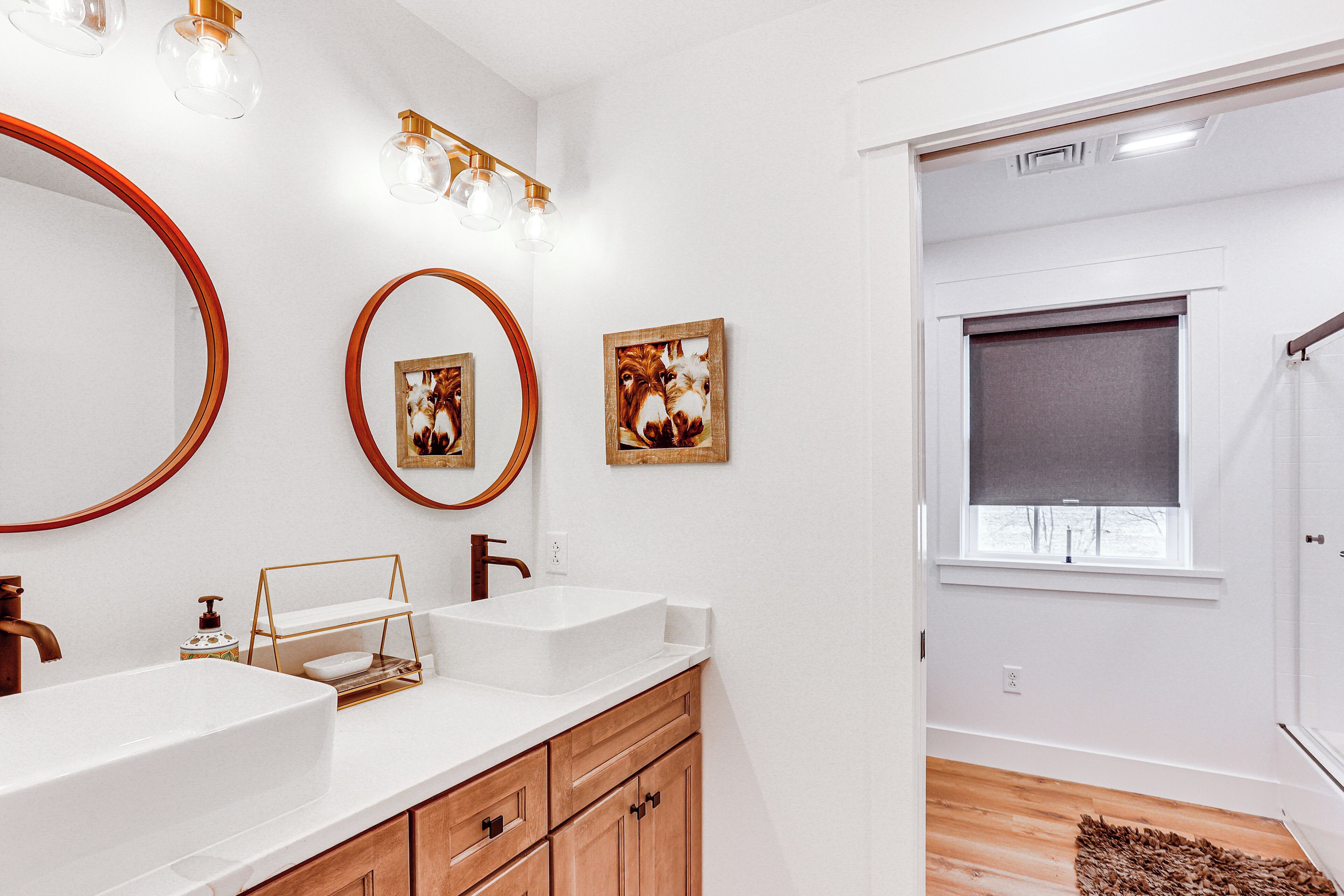 A bathroom with two sinks, wooden cabinets, and a mirror with a gold frame.