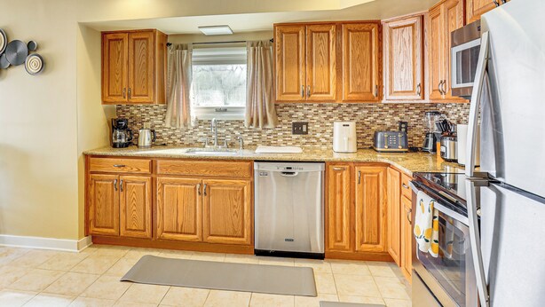 A modern kitchen with wooden cabinets, stainless steel appliances, and a tiled backsplash. - 3 Mi to Berkshire Mall: Suburban Stay w/ Yard! (Sinking Spring)