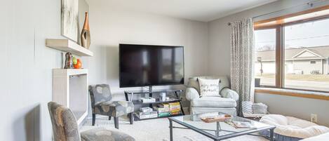 A living room with a flat-screen TV, a sofa, a coffee table, and a bookshelf.