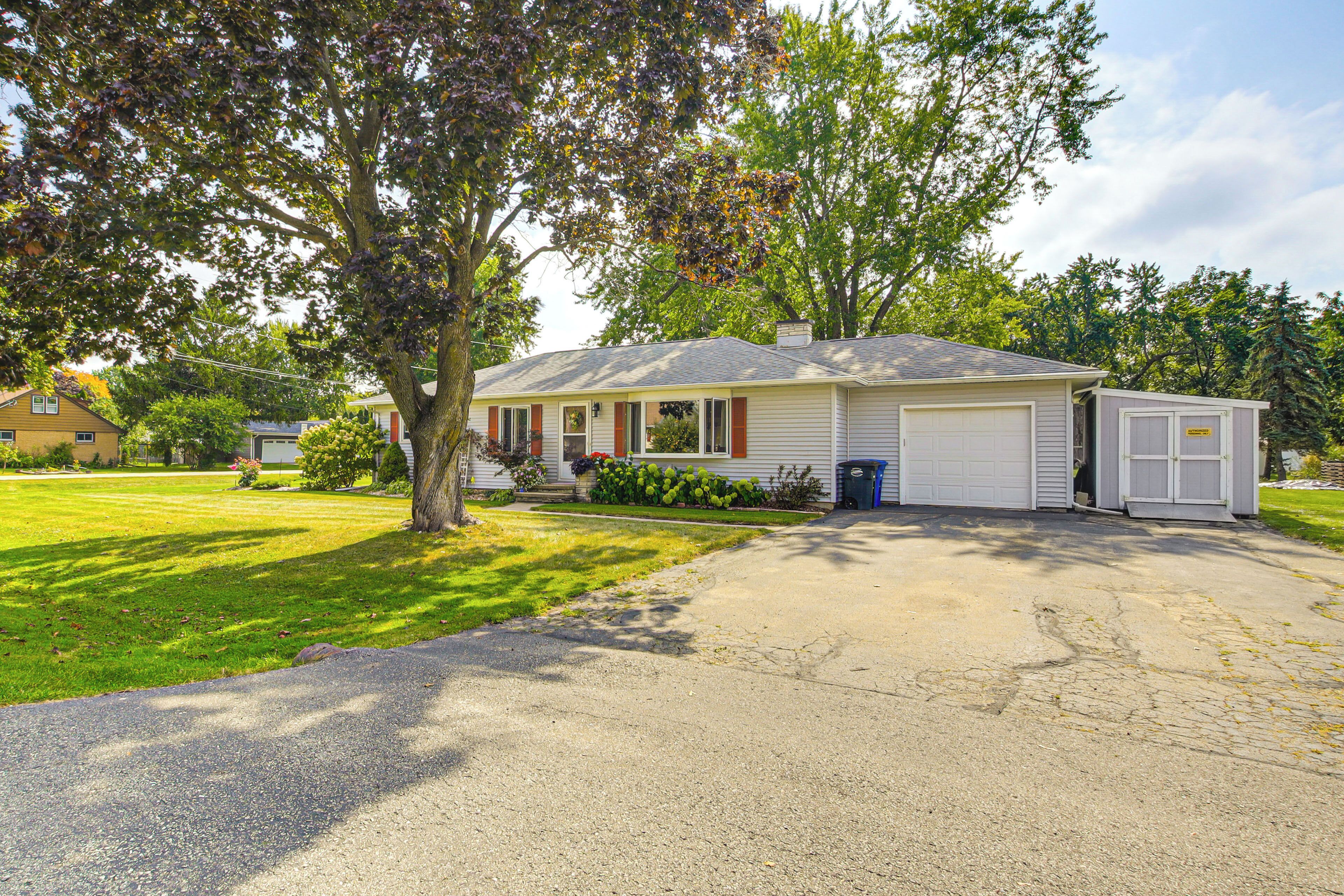 A single-story house with a garage, a front yard, and a tree.