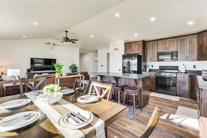 Una cocina moderna con armarios de madera oscura, una isla central y un comedor con una mesa de madera dispuesta para cuatro.