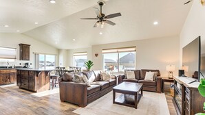 A spacious living room with a large brown leather sofa, a coffee table, and a TV. There is a kitchen area with wooden cabinets and a dining table. - 2 Mi to Beaverhead River: Family-friendly Home! (Dillon)
