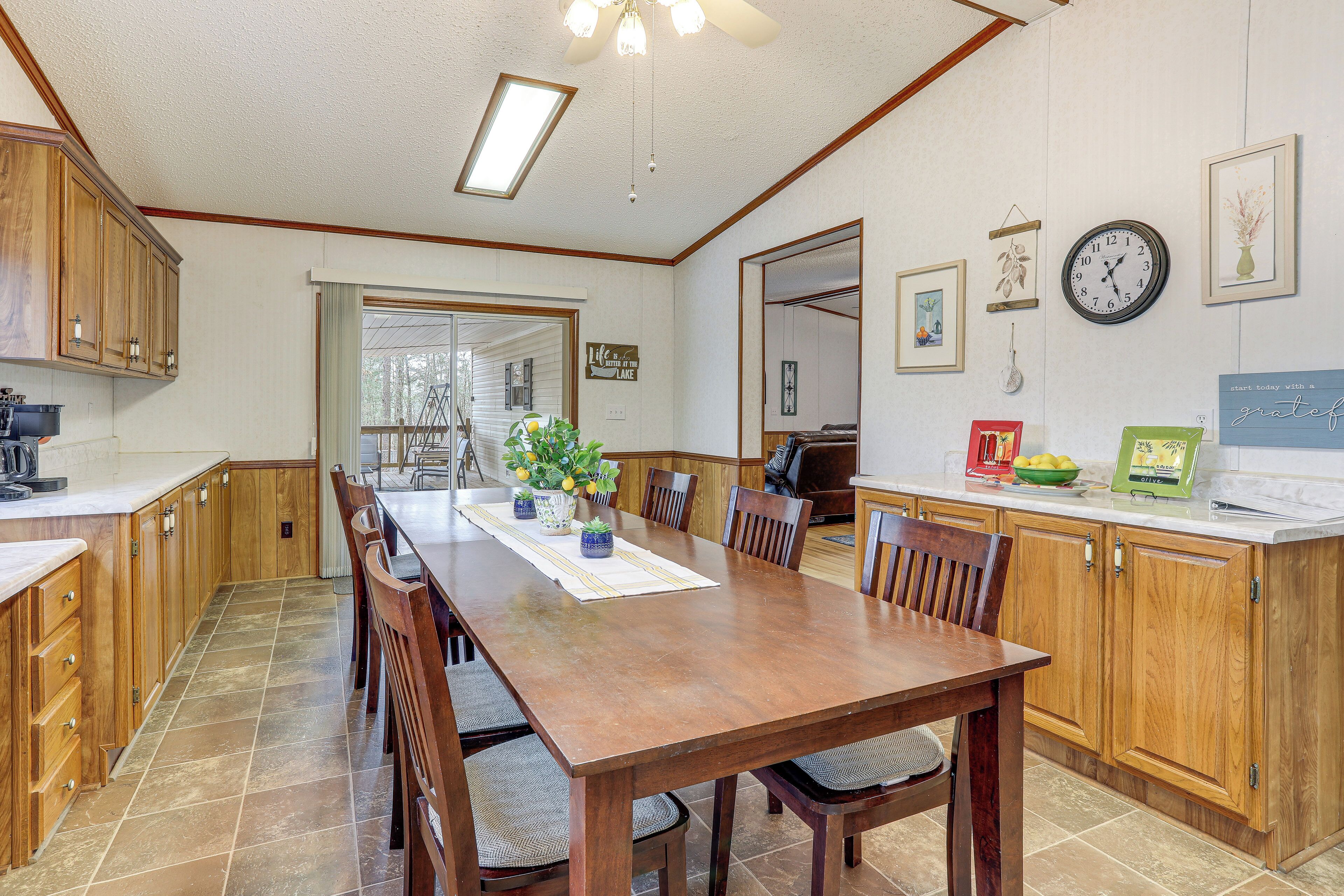 Una cocina amplia con armarios de madera, una gran mesa de comedor y vistas al exterior.