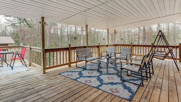 A covered deck with wooden flooring, a blue patterned rug, and outdoor furniture including chairs and a table. - < 1 Mi to Greers Ferry Lake: Dog-friendly Home! (Higden)