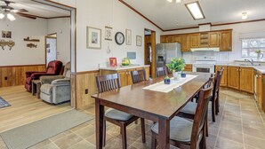 A spacious kitchen with wooden cabinets, a dining table with chairs, and a ceiling fan. - < 1 Mi to Greers Ferry Lake: Dog-friendly Home! (Higden)