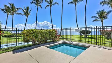 A swimming pool with a view of the ocean and palm trees.