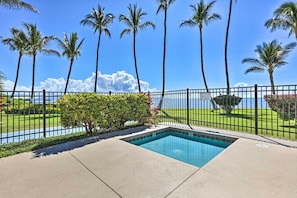 A swimming pool with a view of the ocean and palm trees.