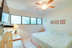 A bedroom with a bed, a desk with a laptop, a ceiling fan, and a window with blinds. - Pool Access: Ocean-view Molokai Shores Condo! (Kaunakakai)